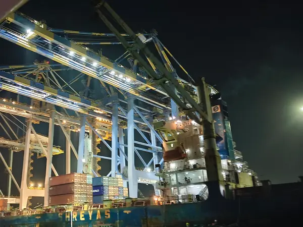 Gantry cranes loading a container ship at night at the International Container Transshipment Terminal in Kochi, India